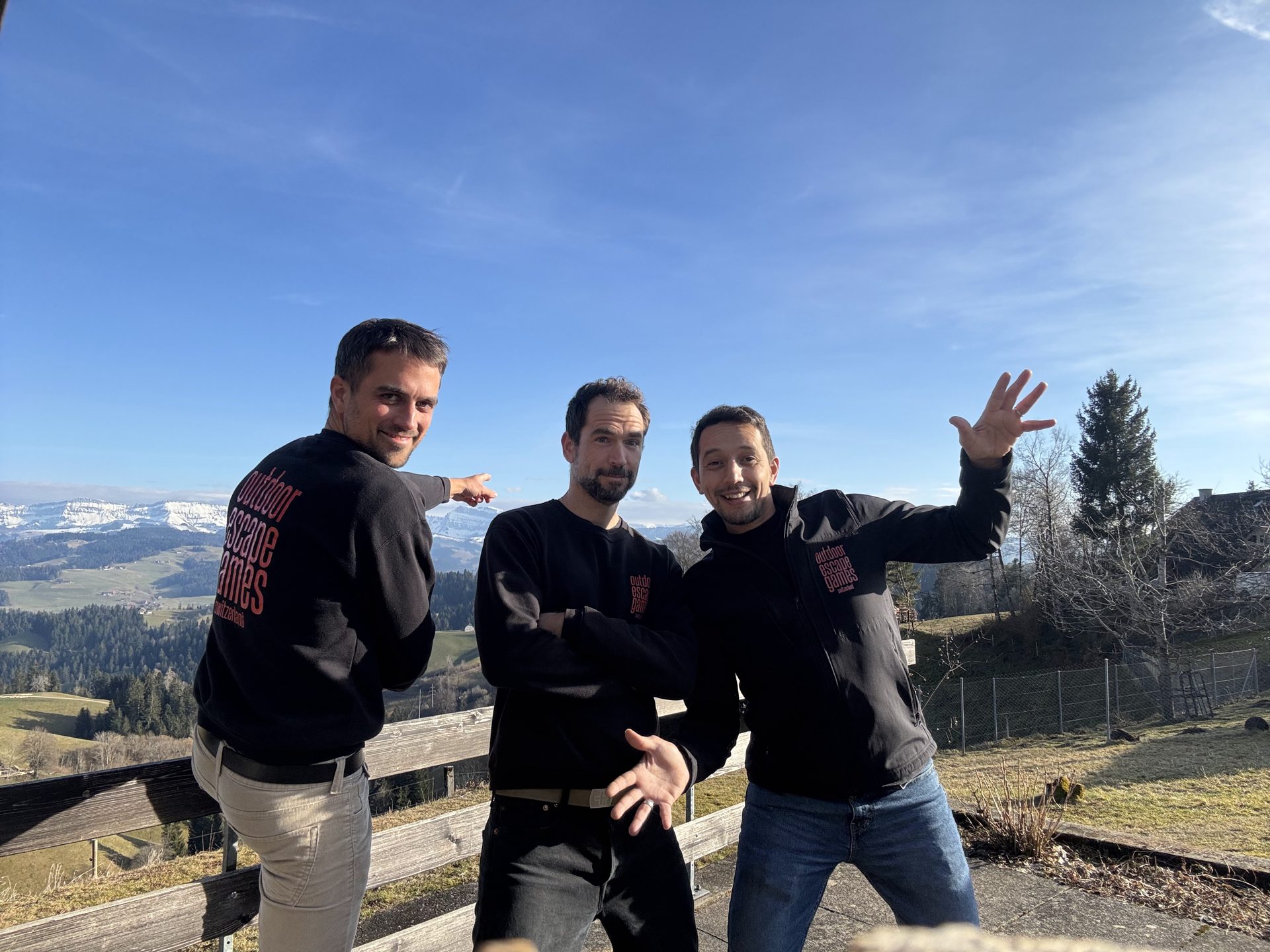 L'équipe Outdoor Escape Games en sweat-shirts noirs devant un panorama des Alpes suisses